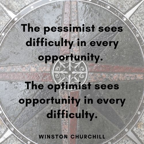 faded overhead view of steel and stone compass rose embedded in a sidewalk, the true direction points are red and pink stone, the diagonal direction points are black stone, the circle is a dark green stone. Text over the image is "The pessimist sees difficulty in every opportunity. The optimist sees opportunity in every difficulty. - Winston Churchill"