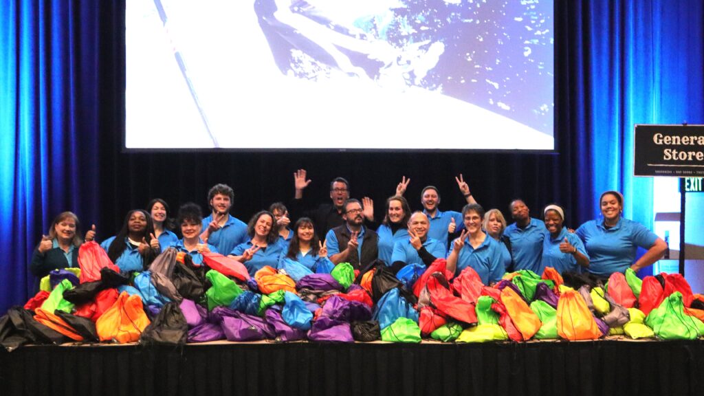 The CEI team standing behind tables covered in bags of different colors filled with donations.